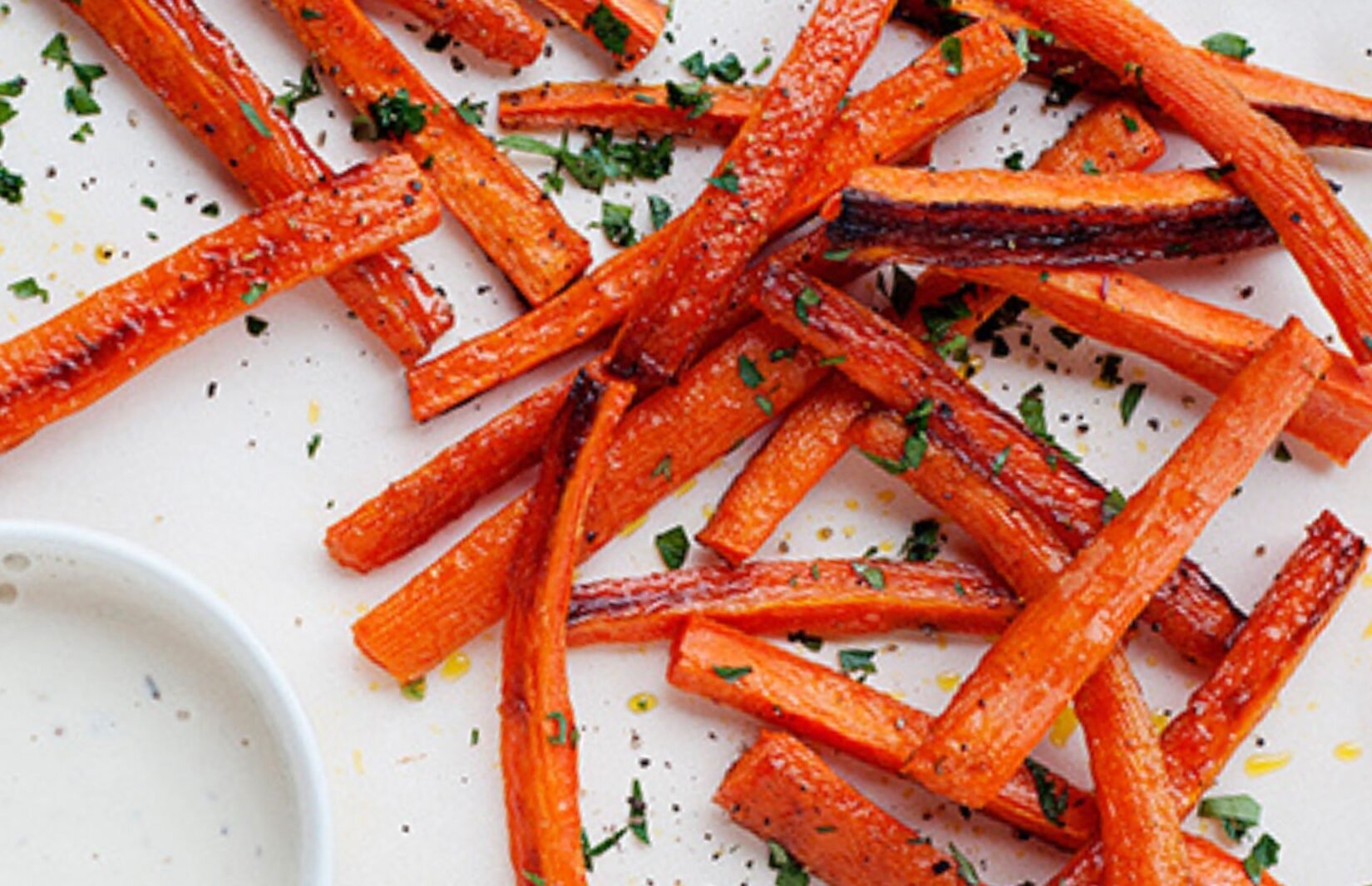 carrot fries on a white plate with a small dish of ranch dressing