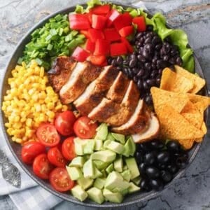 top view of a large bowl of Mexican salad made with corn, tomatoes, chicken, beans, avocado and chips