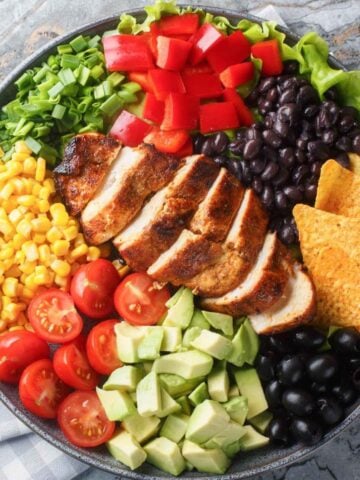 top view of a large bowl of Mexican salad made with corn, tomatoes, chicken, beans, avocado and chips