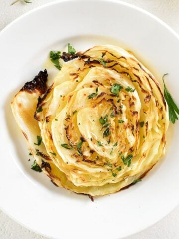 top view of a roasted cabbage steaks in a white dish