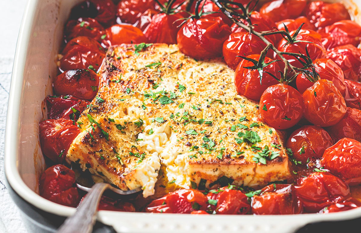 a baking dish with baked feta and cherry tomatoes