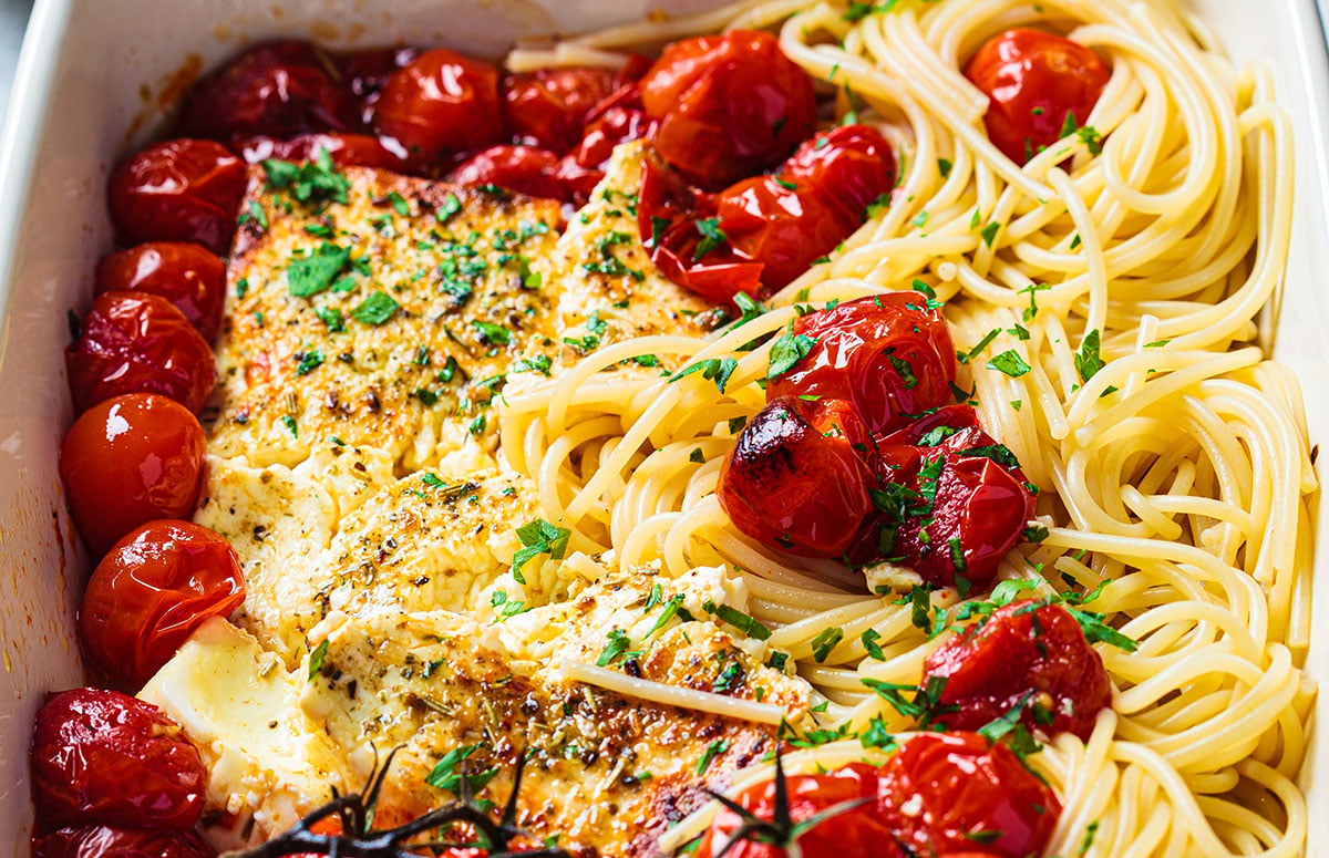 a baking dish with baked feta pasta and cherry tomatoes