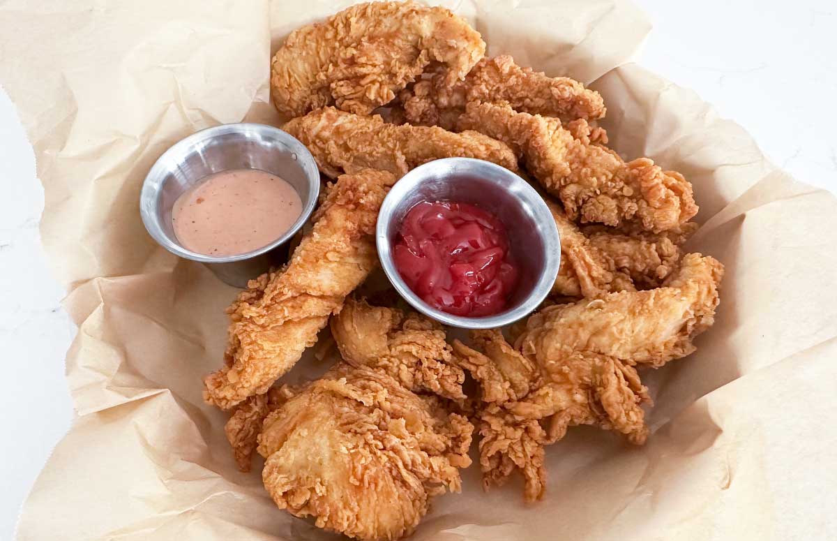 large plate of chicken strips and two dipping sauces