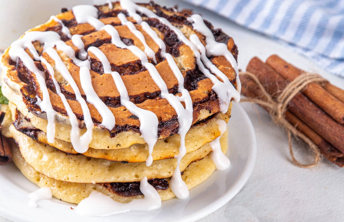 stack of three cinnamon roll pancakes topped with icing