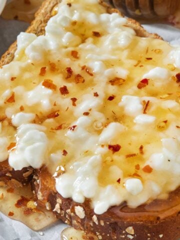a piece of toast with cottage cheese and hot honey