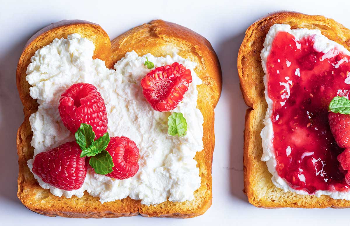 top view of 2 pieces of toast, one with cottage cheese and raspberries, the other with whipped cottage cheese and jam