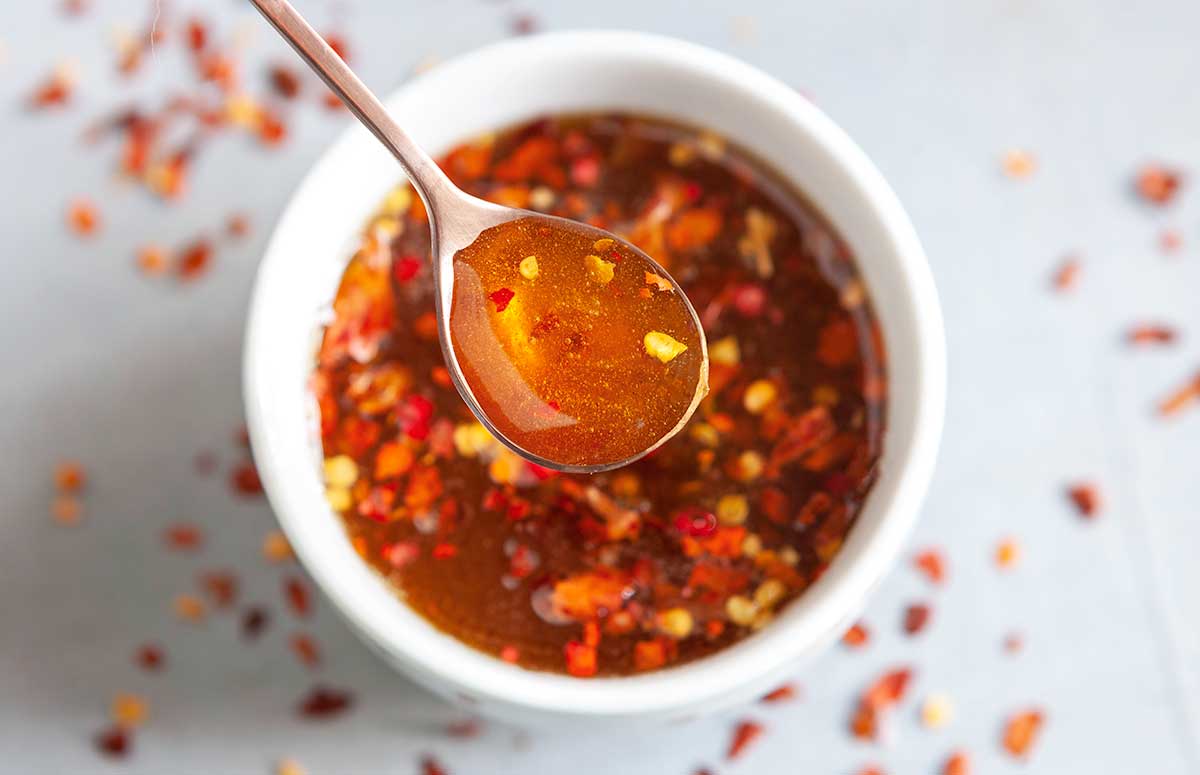 a spoonful of hot honey over a bowl with hot honey