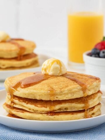 stack of homemade IHOP pancakes on a white plate topped with butter and syrup