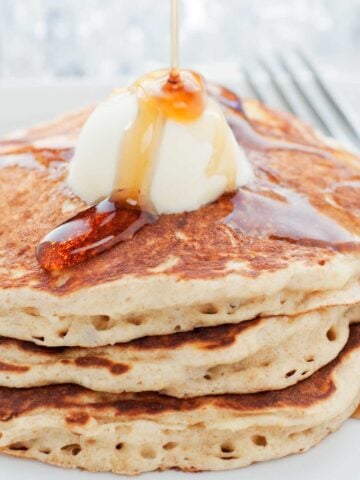three stacked pancakes topped with butter and syrup