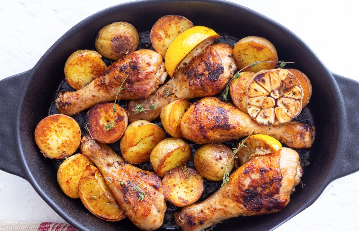 top view of baked chicken legs and potatoes in a baking dish