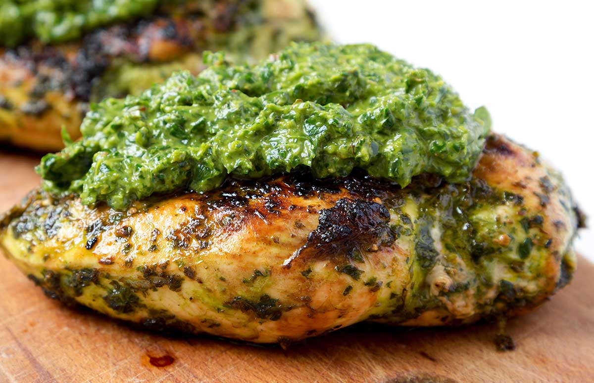 two chicken breasts with chimichurri sauce on top