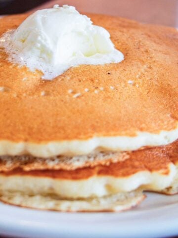 stack of three cracker barrel style pancakes topped with whipped butter