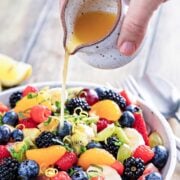 pouring dressing into a fruit salad bowl