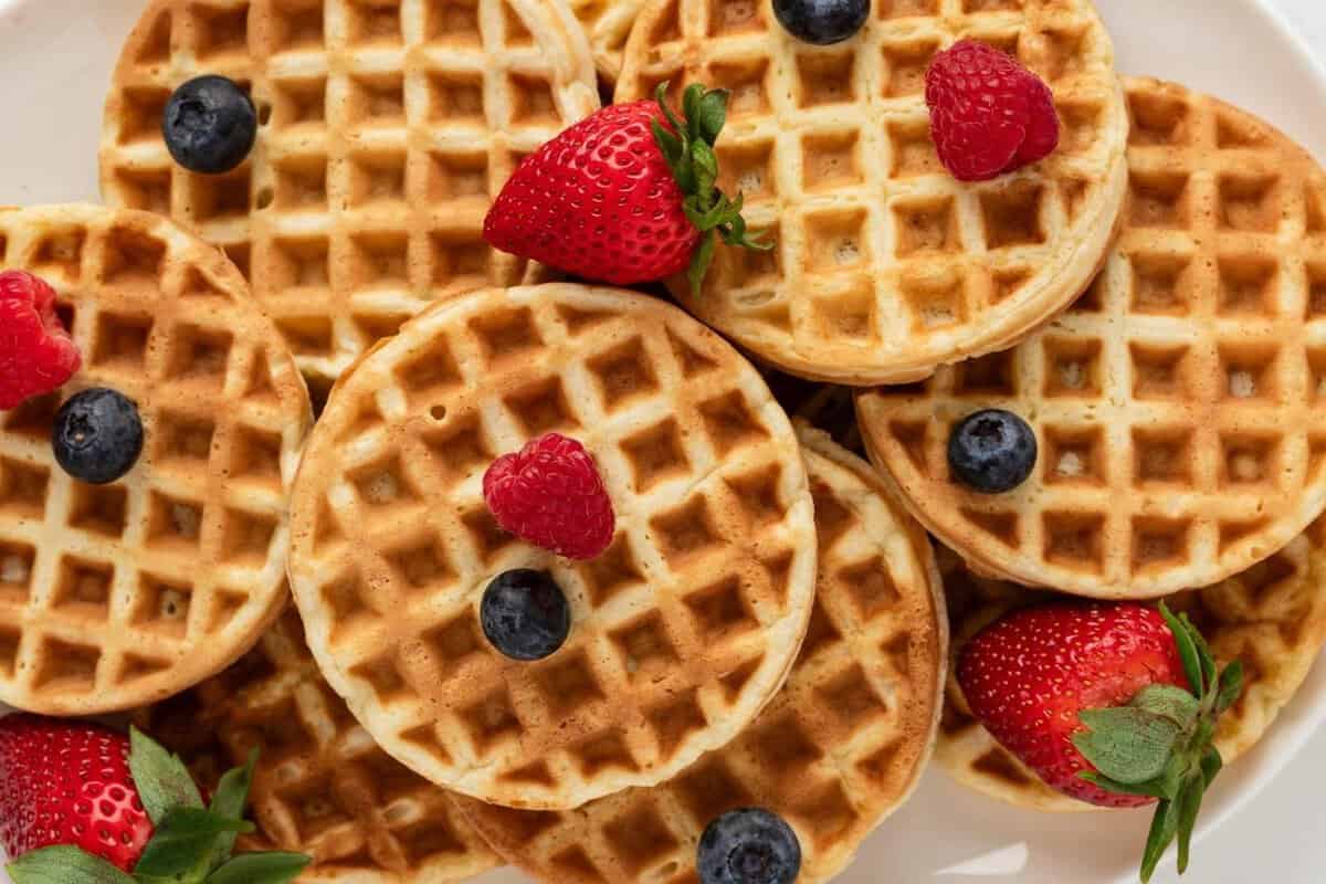 overhead view of protein waffles on a platter topped with a few fresh berries