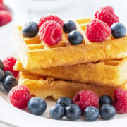 stack of three ricotta pancakes topped with raspberries and blueberries