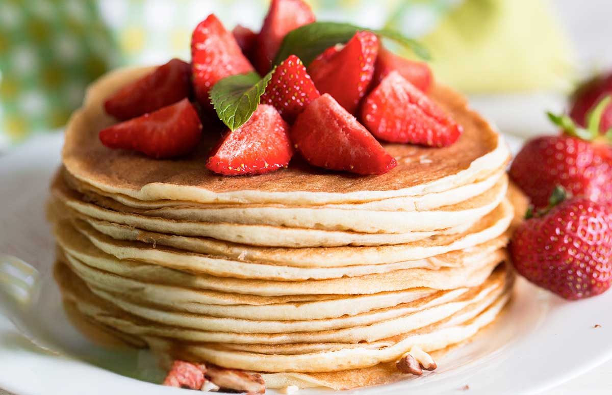 stack of thin pancakes topped with sliced strawberries
