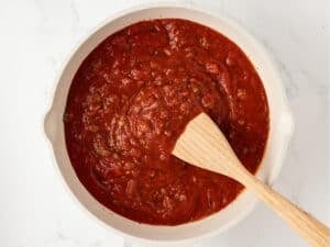 a pot with marinara sauce and ground meat