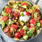 large taco bowl with tomatoes, sour cream, corn and avocado