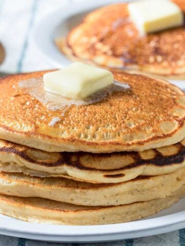 stack of buttermilk pancakes made using a mix on a plate with a pat of butter on top