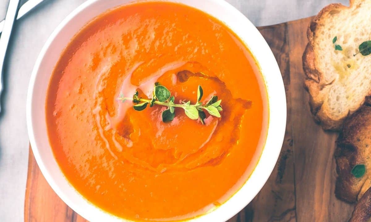 a bowl of creamy tomato soup with toasted bread on the side