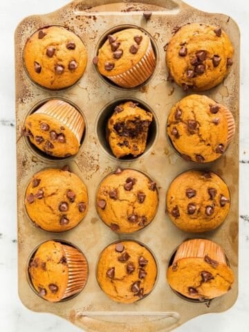overhead view of pumpkin cottage cheese muffins topped with chocolate chips on a baking pan