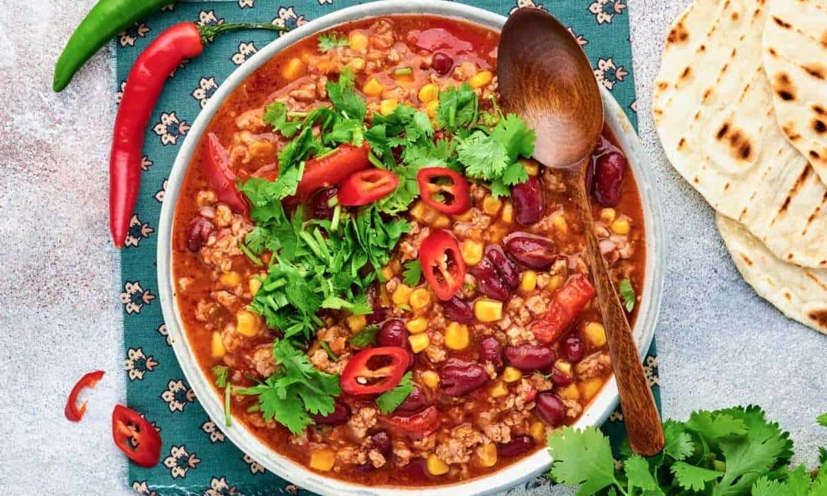 overhead view of corn chili surrounded by chilis and tortillas