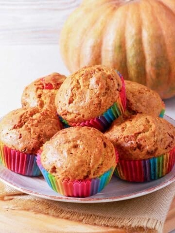 six pumpkin cottage cheese muffins in a white dish and a pumkpin on the back