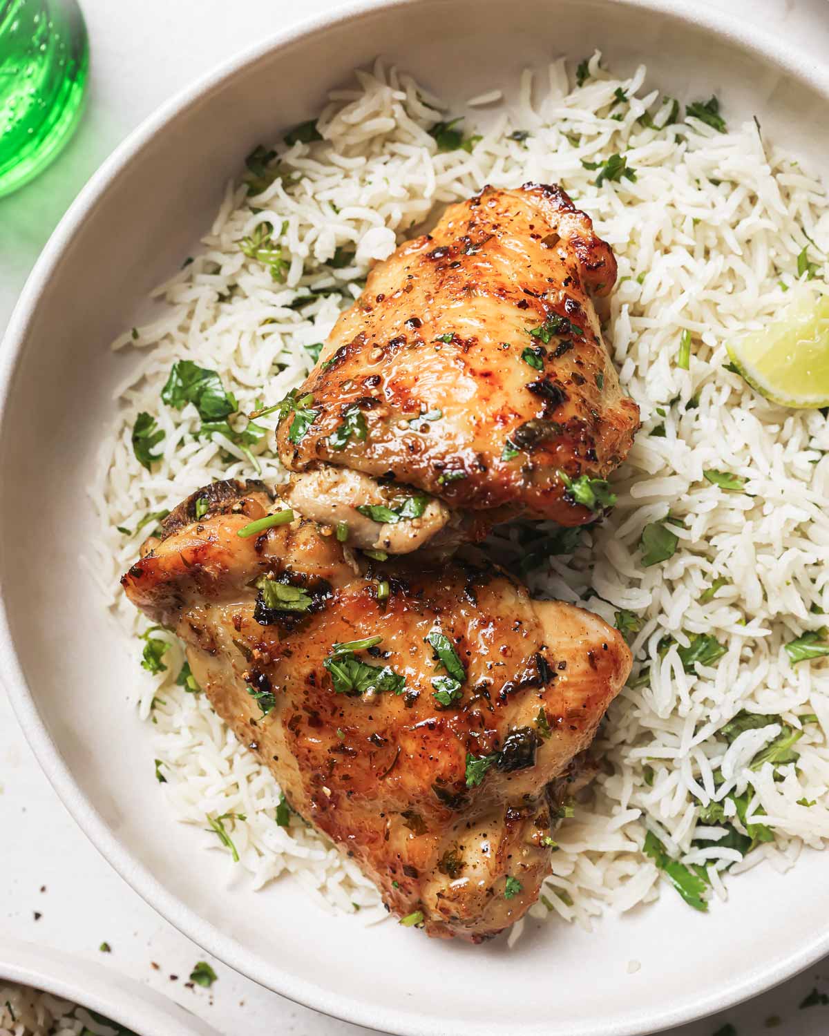top view of two cilantro lime chicken thighs served with rice in a white dish