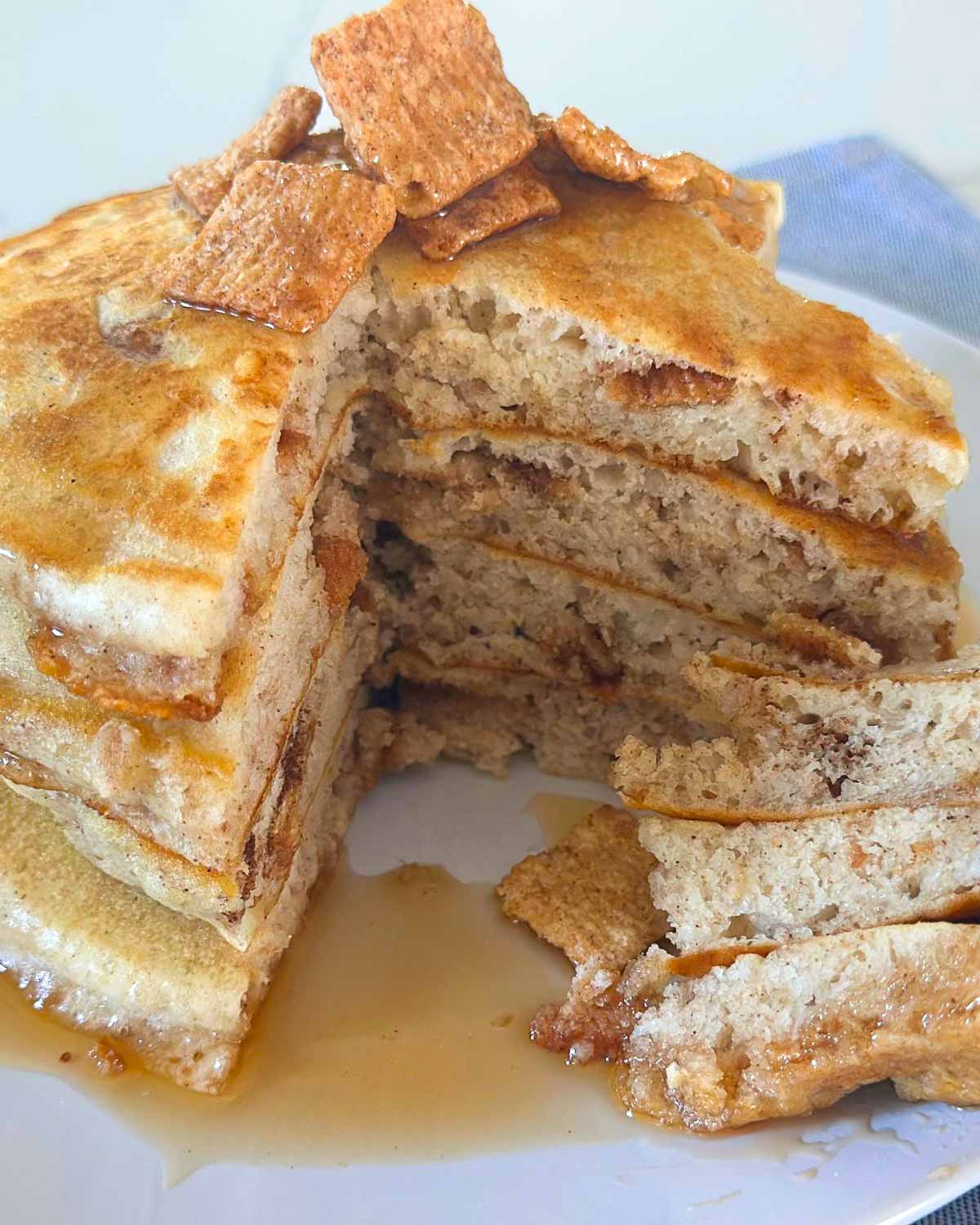 stack of pancakes made with cinnamon toast crunch cereal, sliced on a plate to see how fluffy they are