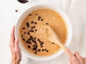overhead view of pumpkin pancake batter with added chocolate chips being mixed in a bowl