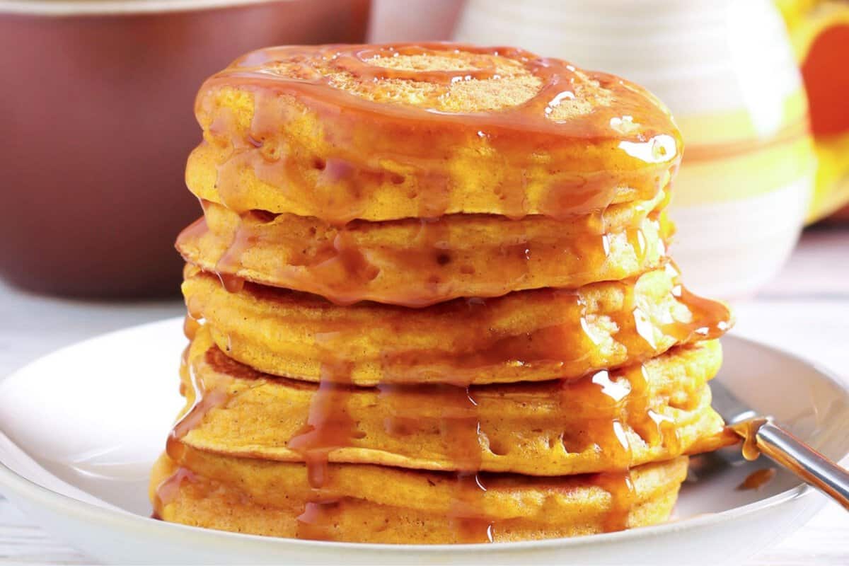 stack of fluffy pumpkin ricotta pancakes with syrup on top on a plate