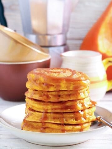 stack of fluffy pumpkin ricotta pancakes with syrup on top on a plate