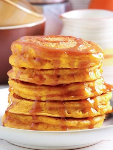 stack of fluffy pumpkin ricotta pancakes with syrup on top on a plate