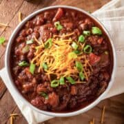 overhead view of beef chili topped with cheese and chives