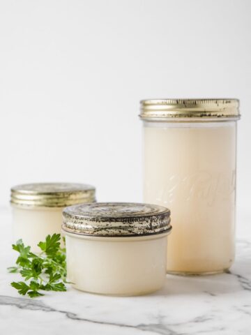 two small jars and a large one filled with chicken broth