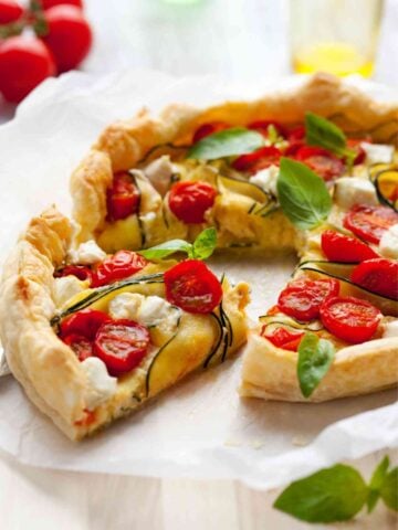 vegetable quiche made with puff pastry crust with one slice taken out of it.