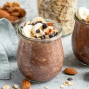 a jar of chocolate protein overnight oats topped with banana slices, chopped walnuts and chocolate chips