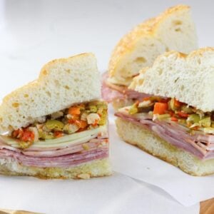 A muffuletta sandwich sliced into quarters on parchment paper