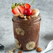 a jar of chocolate overnight oats with banana, strawberries, and chopped almonds