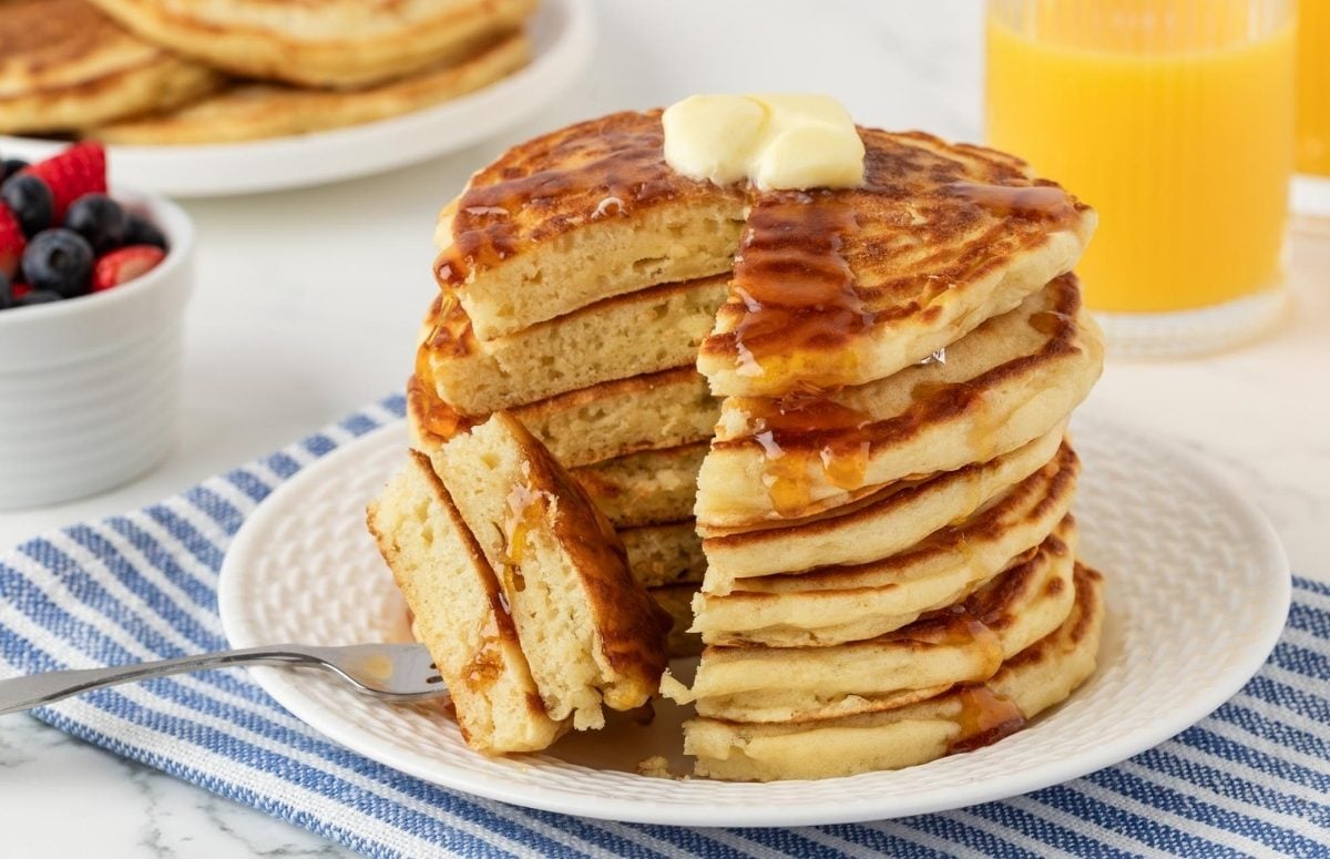large stack of buttermilk pancakes with a forkful taken out