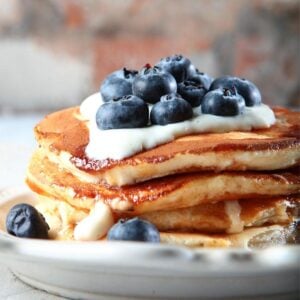 stack of ricotta pancakes topped with blueberries and yogurt