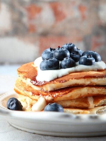 stack of ricotta pancakes topped with blueberries and yogurt