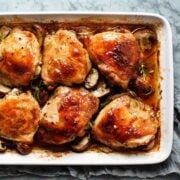 top view of six chicken thighs with mushrooms in a baking dish