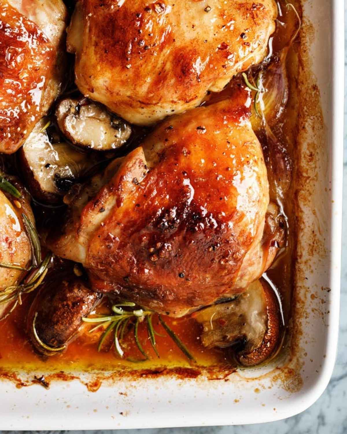 close up of chicken thighs with mushrooms in a baking dish