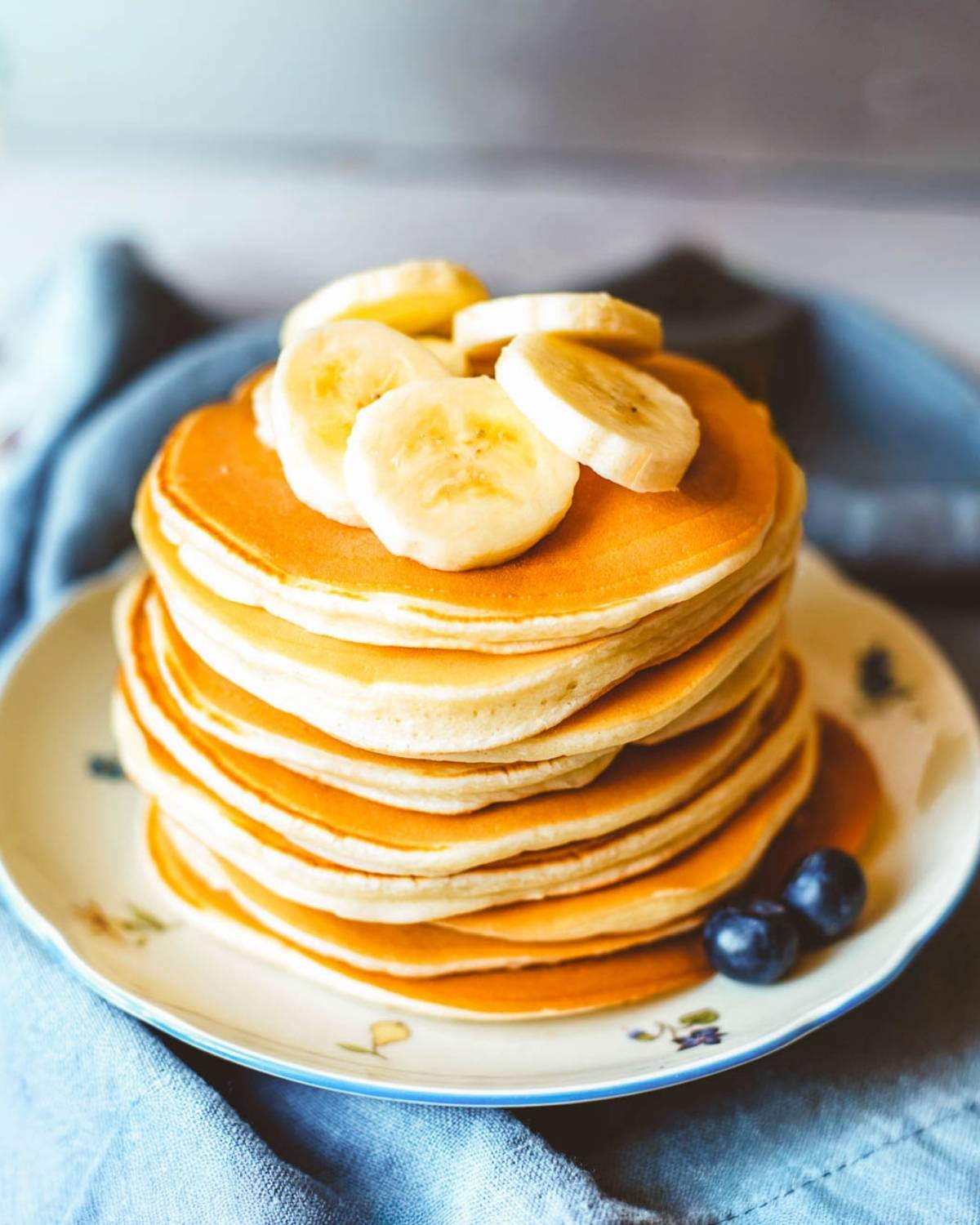 stack of banana ricotta pancakes on a plate topped with sliced bananas