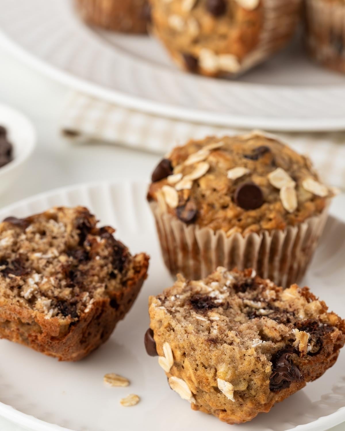 chocolate chip banana oatmeal muffins on a plate one muffin is open in half