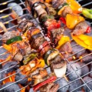 meat and vegetable kabobs threaded through skewers on a grill