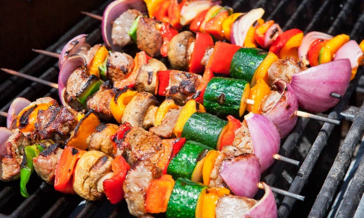 meat and vegetable kabobs threaded through skewers on a grill