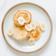 overhead view of simple pancakes for baby on a plate with sliced bananas