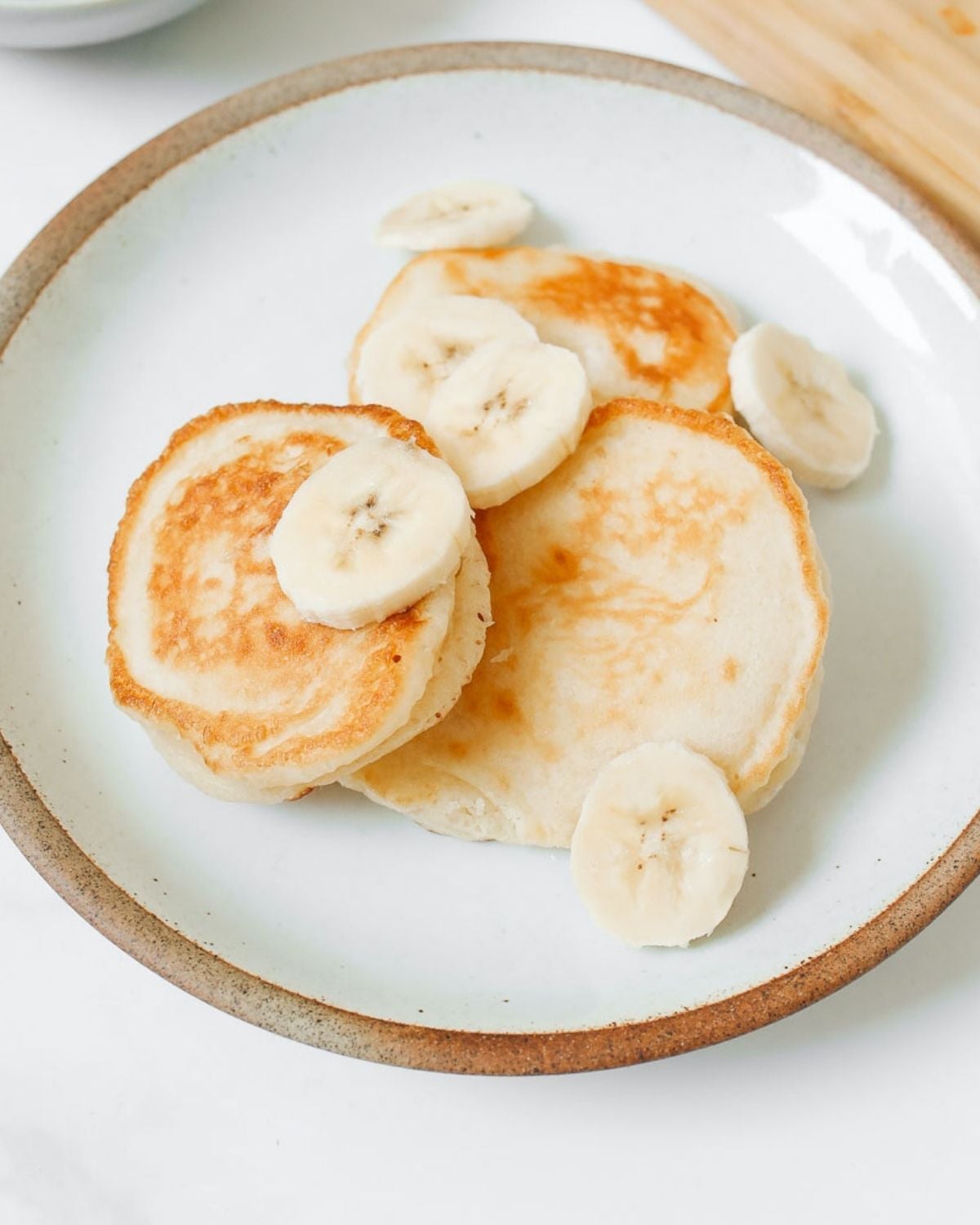 overhead view of simple pancakes for baby on a plate with sliced bananas